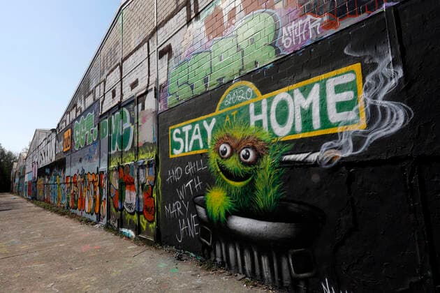 Duesseldorf, Deutschland, 12.04.2020 Das Graffiti Wandbild an der Aussenwand einer Lagerhalle in Duesseldorf - Moersenbroich verwendet den Slogan zuhause zu bleiben ( Stay at Home ) mit der gleichzeitigen Empfehlung dort mit einem Joint zu entspannen ( Chill with Mary Jane )
