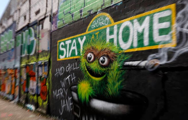 Duesseldorf, Deutschland, 12.04.2020 Das Graffiti Wandbild an der Aussenwand einer Lagerhalle in Duesseldorf - Moersenbroich verwendet den Slogan zuhause zu bleiben ( Stay at Home ) mit der gleichzeitigen Empfehlung dort mit einem Joint zu entspannen ( Chill with Mary Jane )