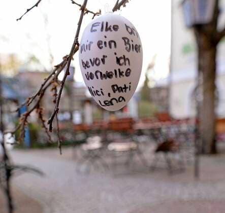 13.04.2020, Ladengeschäfte und Restaurants schliessen wegen Corona-Virus-Pandemie in Bad Wörishofen, Tische und Stühle in einem Biergarten derzeit ohne Gäste. Gäste haben Ostereier mit handgeschriebenen Grüßen hingehängt: Elke bring mir ein Bier bevor ich verwelke 13.04.2020, Geschlossene Restaurants wegen Corona-Virus 13.04.2020, Geschlossene Restaurants wegen Corona-Virus