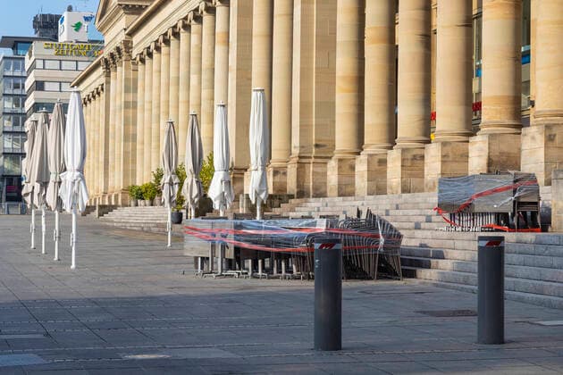 DEU, Deutschland, Baden-Württemberg, Stuttgart, 13.04.2020: Shut down in Stuttgart. Das Corona-Virus legt die Landeshauptstadt lahm. Straßen und Plätze sind menschenleer. Fußgängerzone Königstraße mit Königsbau. Stühle und Tische eines Straßencafes sind unter einer Plastikplane verpackt.