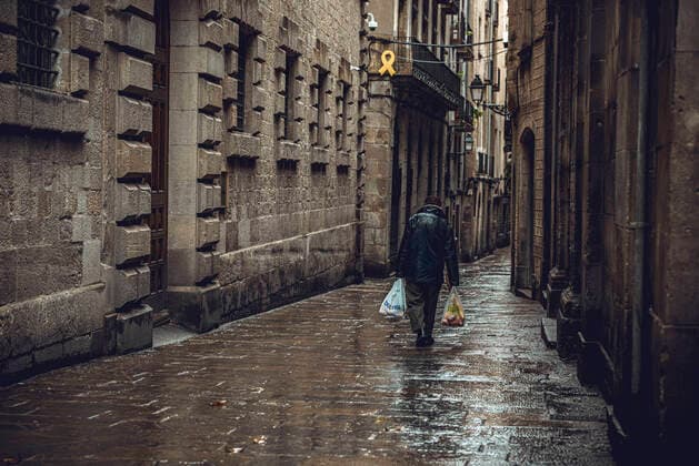 April 13, 2020, Barcelona, Catalonia, Spain: A commuter crosses Barcelona s rainy deserted Gothic Quarter at Easter Monday after more than one month of a nationwide lockdown due to the continuous spread of the virus. Spain registered roughly 300 new fatalities summing up to nearly 17500 in total. Barcelona Spain - ZUMAo105 20200413_zap_o105_011 Copyright: xMatthiasxOesterlex