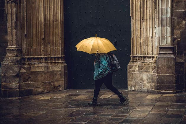 April 13, 2020, Barcelona, Catalonia, Spain: A commuter crosses Barcelona s rainy deserted Gothic Quarter at Easter Monday after more than one month of a nationwide lockdown due to the continuous spread of the virus. Spain registered roughly 300 new fatalities summing up to nearly 17500 in total. Barcelona Spain - ZUMAo105 20200413_zap_o105_013 Copyright: xMatthiasxOesterlex