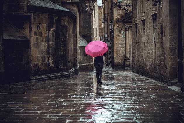 April 13, 2020, Barcelona, Catalonia, Spain: A commuter crosses Barcelona s rainy deserted Gothic Quarter at Easter Monday after more than one month of a nationwide lockdown due to the continuous spread of the virus. Spain registered roughly 300 new fatalities summing up to nearly 17500 in total. Barcelona Spain - ZUMAo105 20200413_zap_o105_015 Copyright: xMatthiasxOesterlex