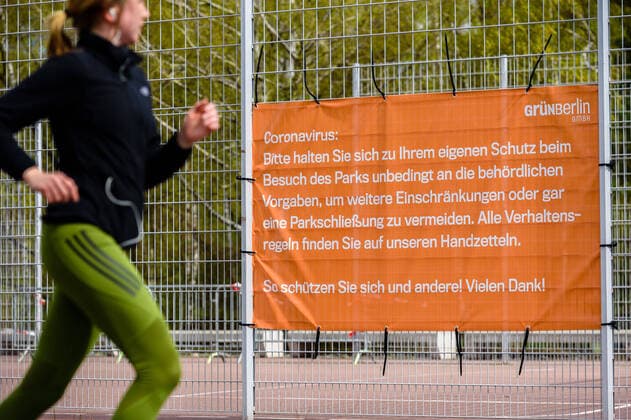 April 13, 2020: An athlete runs past a poster in the park at Gleisdreick with instructions to contain the coronavirus. The German government has considerably restricted public life over the last weeks in order to slow down the spread of the Covid 19 pandemic. - ZUMAs172 20200413_zap_s172_009 Copyright: xJanxScheunertx