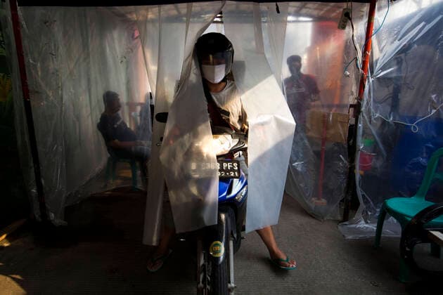 April 13, 2020, Jakarta, DKI Jakarta, IDN: People wearing protective masks who rides a motorcycle across a disinfection chamber at densely populated settlement North Jakarta, Indonesia. Some residents in Jakarta have started to seriously fight the coronavirus (COVID-19) by doing a lockdown and also provide various ways such as the disinfection chamber in access road settlements. Jakarta IDN - ZUMAz107 20200413_zip_z107_010 Copyright: xMuhmmadxZaenuddinx