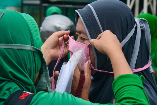 April 13, 2020, Blangpidie, Aceh, Indonesia: A wife of a National Army officer in the city of blangpidie helps a woman to wear a free homemade cloth mask..The Indonesian government requires people to wear masks whenever they are outside their homes in accordance with recommendations from the World Health Organization (WHO) to prevent the spread of COVID-19 in Indonesia. Blangpidie Indonesia - ZUMAs197 20200413_zaa_s197_049 Copyright: xMimixSaputrax
