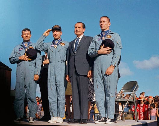 President Richard M. Nixon and the Apollo 13 crew salute the U.S. flag during the post-mission ceremonies at Hickam Air Force Base, Hawaii. Earlier, astronauts John Swigert, Jim Lovell, and Fred W. Haise were presented the Presidential Medal of Freedom by the Chief Executive. Apollo 13, launched on April 11, 1970, was NASA s third crewed mission to the moon. Two days later, on April 13, while en route to the lunar surface, a fault in the electrical system of one of the Service Module s oxygen tanks produced an explosion that caused both oxygen tanks to fail and also led to a loss of electrical power. With the mission aborted, a dedicated team in the Apollo Mission Control Center devoted their efforts to developing a plan to shelter the crew in the lunar module as a lifeboat and retain sufficient resources to bring the spacecraft and its  WAX2020041303 NASA