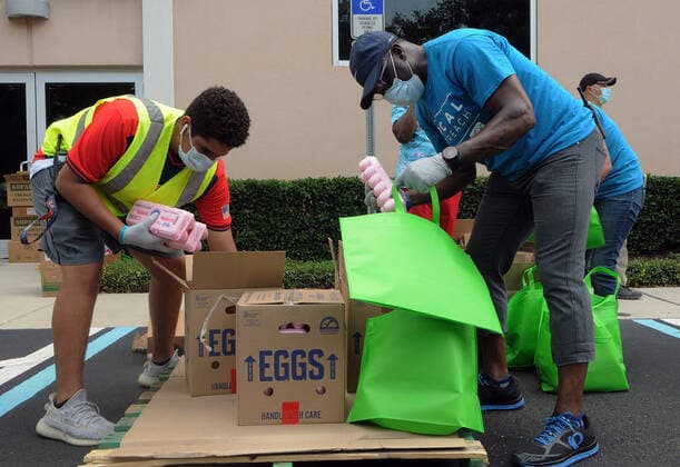 April 13, 2020, Orlando, Florida, United States: Volunteers from Church in the Son place food from the Second Harvest Food Bank of Central Florida into bags for distribution to needy families at a drive-thru event..The numbers of people seeking food assistance in the Orlando area have risen sharply due to job losses caused by the coronavirus pandemic, thereby placing an extra burden on local food pantries. Orlando United States - ZUMAs197 20200413_zaa_s197_308 Copyright: xPaulxHennessyx
