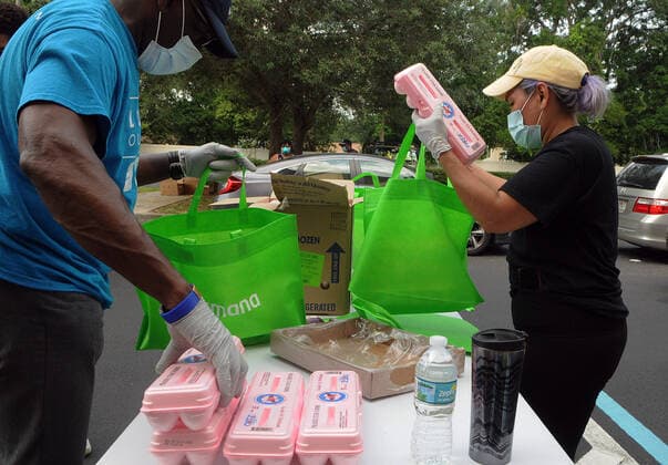 April 13, 2020, Orlando, Florida, United States: Volunteers from Church in the Son place food from the Second Harvest Food Bank of Central Florida into bags for distribution to needy families at a drive-thru event..The numbers of people seeking food assistance in the Orlando area have risen sharply due to job losses caused by the coronavirus pandemic, thereby placing an extra burden on local food pantries. Orlando United States - ZUMAs197 20200413_zaa_s197_307 Copyright: xPaulxHennessyx