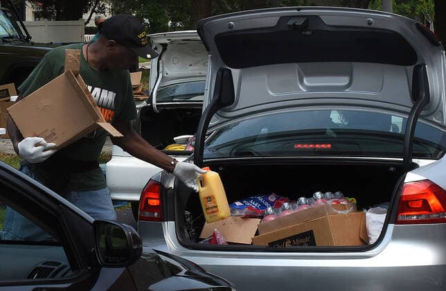 April 13, 2020, Orlando, Florida, United States: A volunteer from Church in the Son place food from the Second Harvest Food Bank of Central Florida into the car of a needy families at a drive-thru event..The numbers of people seeking food assistance in the Orlando area have risen sharply due to job losses caused by the coronavirus pandemic, thereby placing an extra burden on local food pantries. Orlando United States - ZUMAs197 20200413_zaa_s197_309 Copyright: xPaulxHennessyx