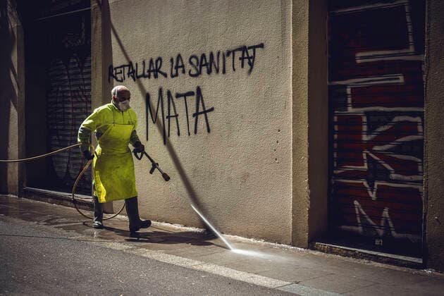 April 14, 2020, Barcelona, Catalonia, Spain: An employee of the municipal cleaning service cleans the street with a high-pressure cleaner passing a wall saying cuts in public health care kill in Barcelona at the end of the first month of a nationwide lockdown due to the continuous spread of COVID-19. Spain registered 300 new fatalities totaling a death toll of over 18000 so far. Barcelona Spain - ZUMAo105 20200414_zap_o105_012 Copyright: xMatthiasxOesterlex