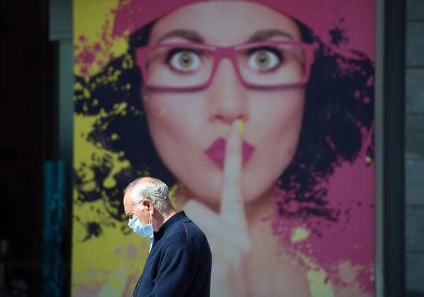 April 14, 2020, Malaga, Spain: A man wearing a face mask as a preventive measure, walks past an advertisement amid coronavirus outbreak..Spaniards get back to their jobs after finishing the standstill of all work activities and services not essential due to the alarm state caused by the outbreak of coronavirus disease (COVID-19) in Spain. Malaga Spain - ZUMAs197 20200414_zaa_s197_091 Copyright: xJesusxMeridax