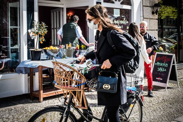 Corona-Life Ein Restaurantbesitzer in der Charlottenburger Knesebeckstrasse macht das Beste aus der Situation, indem er eine ansprechende Aussendekoration vor seinem Geschäft aufstellt. Die zeitgeschichtliche Situation wird durch die Passantin mit Schutzmaske, welche gerade auf ihr Fahrrad steigt unterstrichen. Corona; Coronavirus; Shutdown; Einschränkungen; Umgang mit Corona; Corona-Alltag; Restaurants; OPEN FOR TAKE AWAY; Take away. Berlin Berlin Deu