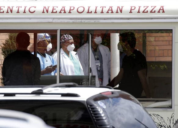 Healthcare workers wearing protective face masks and medical clothes stand outside of an entrance to Wyckoff Heights Medical Center in New York City on Tuesday, April 14, 2020. As of today nearly 285,000 have been infected and more than 14,000 people have died in NY, NJ and CT. There are signs however that the curve is flattening.  NYP20200414123 JOHNxANGELILLO