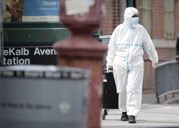 A pedestrian covered head to toe in protective clothes crosses walks on the sidewalk near Wyckoff Heights Medical Center in New York City on Tuesday, April 14, 2020. As of today nearly 285,000 have been infected with Coronavirus and more than 14,000 people have died in NY, NJ and CT. There are signs however that the curve is flattening.  NYP20200414125 JOHNxANGELILLO