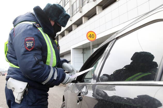 MOSCOW, RUSSIA - APRIL 15, 2020: A traffic police officer carries out an ID check on Volokolamskoye Shosse Motorway during the pandemic of the novel coronavirus disease (COVID-19). Traffic police have set up checkpoints around the city to stop vehicles and see if drivers have permission to travel during the lockdown. On 13 April 2020, the Moscow government introduced a digital permit system aimed at further restricting movement. Under the new scheme, which becomes mandatory from 15 April, people need to apply for permits to travel on a vehicle or public transport around the city. Earlier, on 11 April, the Moscow government restricted vehicles registered outside Moscow Region from entering the Russian capital. Since 31 March 2020, Moscow has been on lockdown. As of 15 April 2020, Russia has reported more than 21,100 confirmed cases of the  TS0D5C64