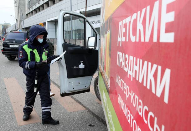 MOSCOW, RUSSIA - APRIL 15, 2020: A traffic police officer in a face mask carries out an ID check on Volokolamskoye Shosse Motorway during the pandemic of the novel coronavirus disease (COVID-19). Traffic police have set up checkpoints around the city to stop vehicles and see if drivers have permission to travel during the lockdown. On 13 April 2020, the Moscow government introduced a digital permit system aimed at further restricting movement. Under the new scheme, which becomes mandatory from 15 April, people need to apply for permits to travel on a vehicle or public transport around the city. Earlier, on 11 April, the Moscow government restricted vehicles registered outside Moscow Region from entering the Russian capital. Since 31 March 2020, Moscow has been on lockdown. As of 15 April 2020, Russia has reported more than 21,100 confirme  TS0D5C65
