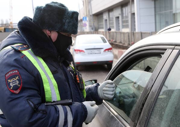 MOSCOW, RUSSIA - APRIL 15, 2020: A traffic police officer in a face mask carries out an ID check on Volokolamskoye Shosse Motorway during the pandemic of the novel coronavirus disease (COVID-19). Traffic police have set up checkpoints around the city to stop vehicles and see if drivers have permission to travel during the lockdown. On 13 April 2020, the Moscow government introduced a digital permit system aimed at further restricting movement. Under the new scheme, which becomes mandatory from 15 April, people need to apply for permits to travel on a vehicle or public transport around the city. Earlier, on 11 April, the Moscow government restricted vehicles registered outside Moscow Region from entering the Russian capital. Since 30 March 2020, Moscow has been on lockdown. As of 15 April 2020, Russia has reported more than 21,100 confirme  TS0D5C78