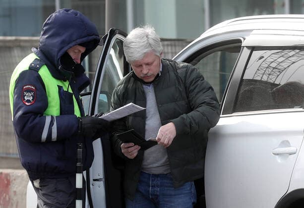 MOSCOW, RUSSIA - APRIL 15, 2020: A traffic police officer carries out an ID check on Volokolamskoye Shosse Motorway during the pandemic of the novel coronavirus disease (COVID-19). Traffic police have set up checkpoints around the city to stop vehicles and see if drivers have permission to travel during the lockdown. On 13 April 2020, the Moscow government introduced a digital permit system aimed at further restricting movement. Under the new scheme, which becomes mandatory from 15 April, people need to apply for permits to travel on a vehicle or public transport around the city. Earlier, on 11 April, the Moscow government restricted vehicles registered outside Moscow Region from entering the Russian capital. Since 30 March 2020, Moscow has been on lockdown. As of 15 April 2020, Russia has reported more than 21,100 confirmed cases of the  TS0D5C79