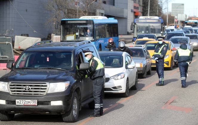 MOSCOW, RUSSIA - APRIL 15, 2020: Traffic police officers in face masks carry out an ID check on Volokolamskoye Shosse Motorway during the pandemic of the novel coronavirus disease (COVID-19). Traffic police have set up checkpoints around the city to stop vehicles and see if drivers have permission to travel during the lockdown. On 13 April 2020, the Moscow government introduced a digital permit system aimed at further restricting movement. Under the new scheme, which becomes mandatory from 15 April, people need to apply for permits to travel on a vehicle or public transport around the city. Earlier, on 11 April, the Moscow government restricted vehicles registered outside Moscow Region from entering the Russian capital. Since 30 March 2020, Moscow has been on lockdown. As of 15 April 2020, Russia has reported more than 21,100 confirmed ca  TS0D5C98