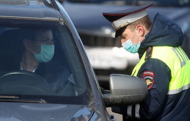 MOSCOW, RUSSIA - APRIL 15, 2020: A traffic police officer in a face mask carries out an ID check on Volokolamskoye Shosse Motorway during the pandemic of the novel coronavirus disease (COVID-19). Traffic police have set up checkpoints around the city to stop vehicles and see if drivers have permission to travel during the lockdown. On 13 April 2020, the Moscow government introduced a digital permit system aimed at further restricting movement. Under the new scheme, which becomes mandatory from 15 April, people need to apply for permits to travel on a vehicle or public transport around the city. Earlier, on 11 April, the Moscow government restricted vehicles registered outside Moscow Region from entering the Russian capital. Since 30 March 2020, Moscow has been on lockdown. As of 15 April 2020, Russia has reported more than 21,100 confirme  TS0D5C9C