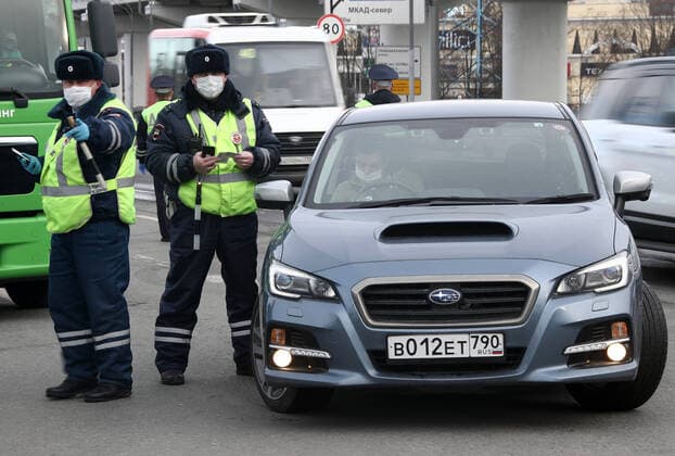MOSCOW, RUSSIA - APRIL 15, 2020: Traffic police officers in face masks carry out ID checks on Leningradskoye Shosse Motorway at the entrance to Moscow during the pandemic of the novel coronavirus disease (COVID-19). Traffic police have set up checkpoints around the city to stop vehicles and see if drivers have permission to travel during the lockdown. On 13 April 2020, the Moscow government introduced a digital permit system aimed at further restricting movement. Under the new scheme, which becomes mandatory from 15 April, people need to apply for permits to travel on a vehicle or public transport around the city. Earlier, on 11 April, the Moscow government restricted vehicles registered outside Moscow Region from entering the Russian capital. Since 30 March 2020, Moscow has been on lockdown. As of 15 April 2020, Russia has reported more  TS0D5C7F