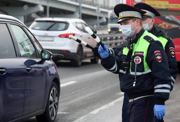 MOSCOW, RUSSIA - APRIL 15, 2020: Traffic police officers in face masks carry out ID checks on Leningradskoye Shosse Motorway at the entrance to Moscow during the pandemic of the novel coronavirus disease (COVID-19). Traffic police have set up checkpoints around the city to stop vehicles and see if drivers have permission to travel during the lockdown. On 13 April 2020, the Moscow government introduced a digital permit system aimed at further restricting movement. Under the new scheme, which becomes mandatory from 15 April, people need to apply for permits to travel on a vehicle or public transport around the city. Earlier, on 11 April, the Moscow government restricted vehicles registered outside Moscow Region from entering the Russian capital. Since 30 March 2020, Moscow has been on lockdown. As of 15 April 2020, Russia has reported more  TS0D5C81