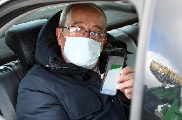 MOSCOW, RUSSIA - APRIL 15, 2020: A motorist in a face mask shows a digital code on his smartphone during an ID check on Leningradskoye Shosse Motorway at the entrance to Moscow during the pandemic of the novel coronavirus disease (COVID-19). Traffic police have set up checkpoints around the city to stop vehicles and see if drivers have permission to travel during the lockdown. On 13 April 2020, the Moscow government introduced a digital permit system aimed at further restricting movement. Under the new scheme, which becomes mandatory from 15 April, people need to apply for permits to travel on a vehicle or public transport around the city. Earlier, on 11 April, the Moscow government restricted vehicles registered outside Moscow Region from entering the Russian capital. Since 30 March 2020, Moscow has been on lockdown. As of 15 April 2020,  TS0D5CA3