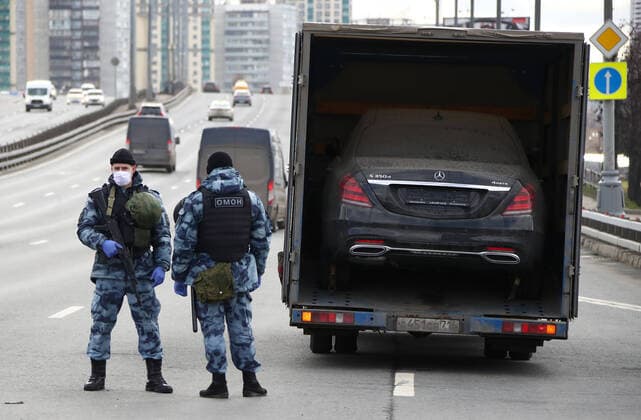 MOSCOW, RUSSIA - APRIL 15, 2020: Armed Rosgvardia OMON officers in face masks stand guard at a checkpoint on Leningradskoye Shosse Motorway at the entrance to Moscow during the pandemic of the novel coronavirus disease (COVID-19). Traffic police have set up checkpoints around the city to stop vehicles and see if drivers have permission to travel during the lockdown. On 13 April 2020, the Moscow government introduced a digital permit system aimed at further restricting movement. Under the new scheme, which becomes mandatory from 15 April, people need to apply for permits to travel on a vehicle or public transport around the city. Earlier, on 11 April, the Moscow government restricted vehicles registered outside Moscow Region from entering the Russian capital. Since 30 March 2020, Moscow has been on lockdown. As of 15 April 2020, Russia has  TS0D5CE0