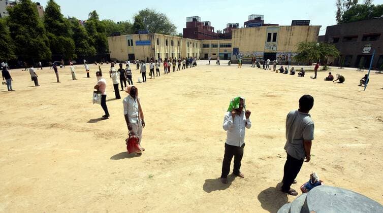 NEW DELHI, INDIA - APRIL 15: Stranded migrant workers and homeless people queue to collect food during the lockdown, at Sunlight colony, Seema Puri area on April 15, 2020 in New Delhi, India. (Photo by Sonu Mehta Hindustan Times) India Extends Nationwide Coronavirus Lockdown Until May 3