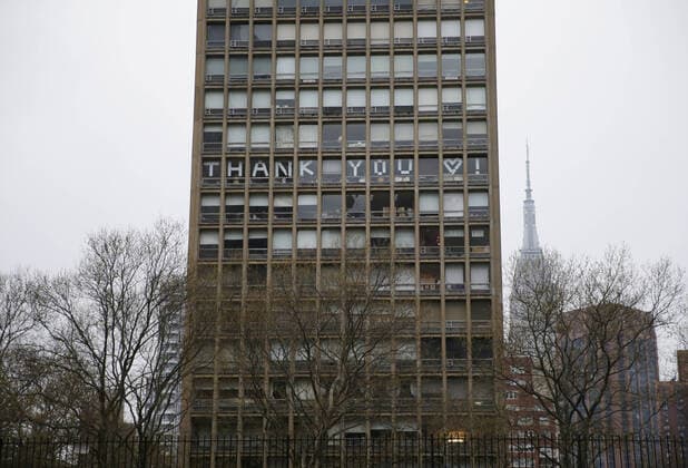 The words Thank You is spelled out in the windows of a building directly across from NYU Langone hospital when FDNY firefighters, NYPD police officers and pedestrians applaud and show their gratitude to medical staff and essential workers on the front lines of the coronavirus pandemic in New York City on Friday, April 17, 2020. The city s coronavirus death toll continued to climb with over 700 new COVID-19 fatalities bringing the total to over 12,000 to date.  NYP20200417113 JOHNxANGELILLO