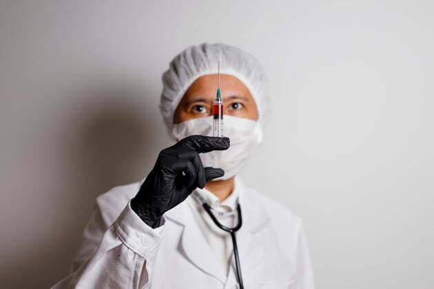 Eine Virologin posiert mit einer Spritze zur Impfung gegen das Corona-Virus (Symbolfoto mit Model)