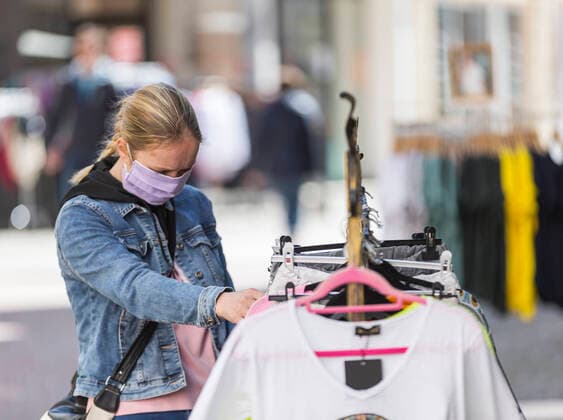 Deutschland, , , 20.04.2020, Presse, COVID-19 Deutschland faehrt langsam wieder hoch Bild: In Hessen haben die Geschaefte wieder geoeffnet, in Bayern nicht. Das wirkt sich vor allem auf die Osthessische Stadt Fulda aus, die nicht weit von der Bayerischen Landesgrenze entfernt liegt. Eine Frau schaut sich mit Mundschutz in Fulda Kleidung an geht shoppen. Copyright: HMBxMedia OliverxMueller