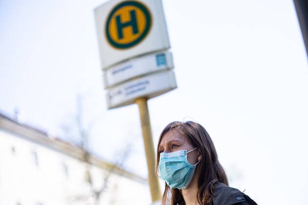 Maskenpflicht im ÖPNV in Berlin, Die Menschen in Berlin müssen ab kommende Woche (27. April) im Öffentlichen Personen-Nahverkehr (ÖPNV) in Bussen, S- und U-Bahnen einen Mund-Nasen-Schutz tragen. Eine Junge Frau steht an einer Bushaltestelle mit einem Mund-Nasen-Schutz. Berlin Berlin Deutschland