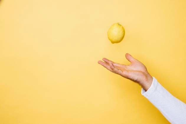 Studio shot of hand of person tossing up lemon model released Symbolfoto DAWF01394