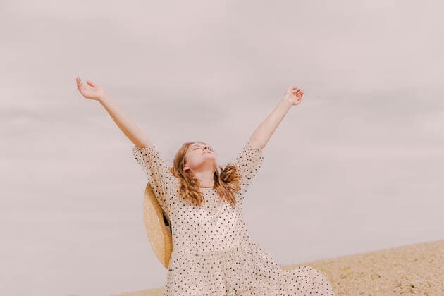IMAGO Creative: Kulturelle Folgen der Pandemie: Gesundheitsbewußtsein und Alleinsein Woman in vintage dress raising her arms on a remote field in the countryside model released Symbolfoto ERRF03089