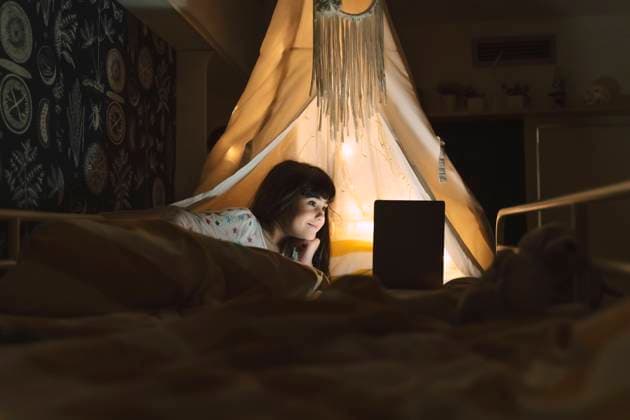 IMAGO Creative, Weihnachten, Tradition: Weihnachtsfilme sehen Smiling girl lying on bed using laptop model released Symbolfoto property released ERRF03197