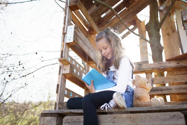 IMAGO Creative: Bildung, Schreiben Girl sitting in garden at tree house and writing something in her blue diary model released Symbolfoto property released HMEF00883
