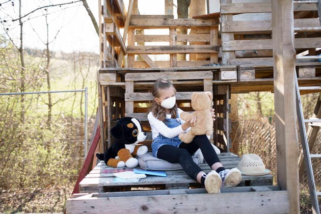 Girl with protective mask sitting in the garden at tree house and playing alone with her cuddly toys during the corona quarantine model released Symbolfoto property released HMEF00884