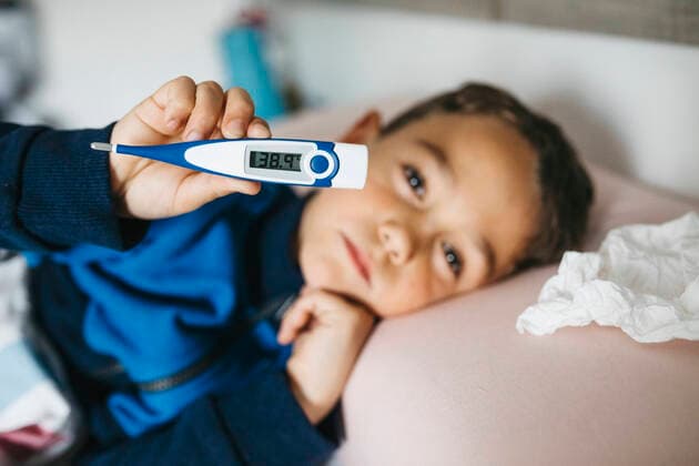 Portrait of sick little boy lying in bed showing digital thermometer model released Symbolfoto property released JRFF04247