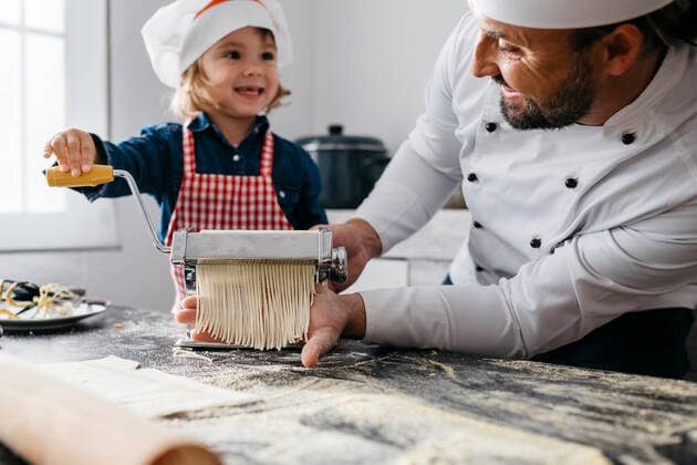 IMAGO Creative: Vaterschaft Father and daughter making homemade pasta with pasta machine in kitchen at home model released Symbolfoto property released JRFF04295