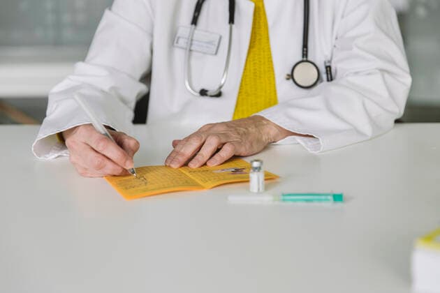 Doctor filling out immunization card model released Symbolfoto property released MFF05486