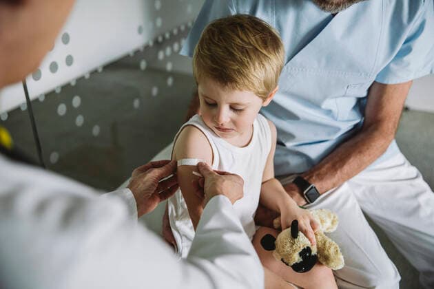Pediatrist putting band-aid onto arm of toddler after vaccination model released Symbolfoto property released MFF05527