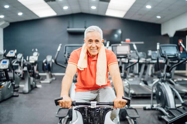 Portrait of smiling senior man practising at exercise machine in gym model released Symbolfoto property released OCMF01102