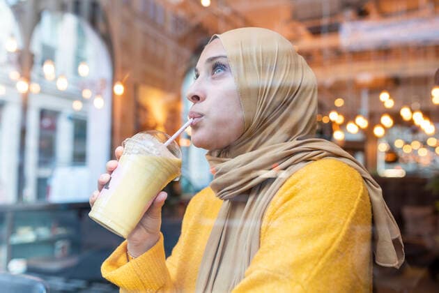 IMAGO Creative: Dichotomien, Reflexionen Young woman wearing hijab drinking smoothie in a cafe model released Symbolfoto  WPEF02713