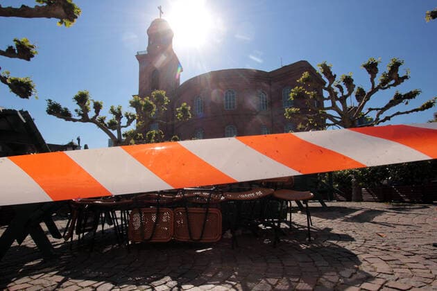 Absperrband vor gestapelten Tischen und Stühlen eines geschlossenen Café s auf dem Paulsplatz vor der Paulskirche bei schönstem Sonnenschein in der Innenstadt Frankfurt, Hessen, Deutschland