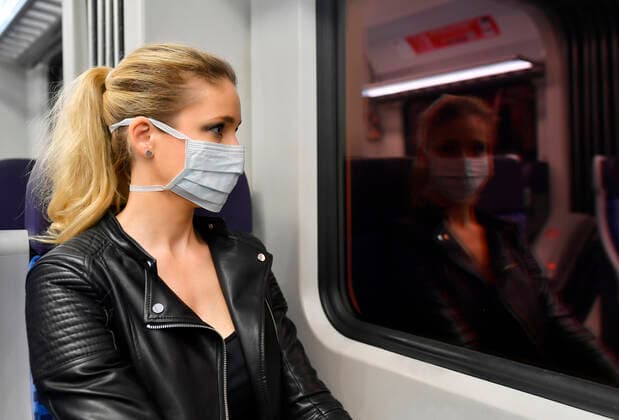 Frau mit Mundschutzmaske, sitzt in Zug, spiegelt sich in S-Bahn, Corona-Krise, Stuttgart, Baden-Württemberg, Deutschland Coronavirus