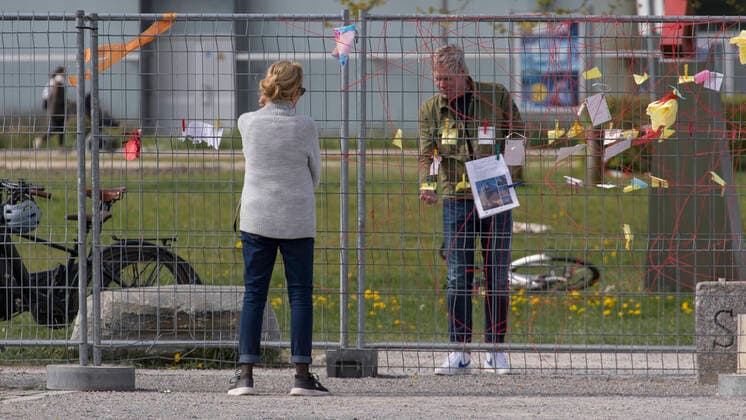 Kreuzlingen, Switzerland - April 20, 2020: A woman and a man at the border fence between Switzerland and Germany. Different people are separated from each other. The border fence separates the two places Kreuzlingen (Switzerland) and Constance (Germany) on Lake Constance. The man was reading the various messages that were posted on the border fence. Panedmie