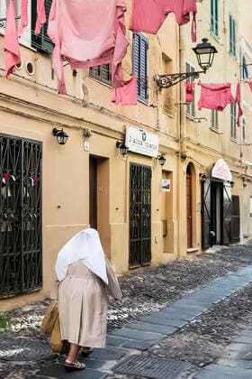 IMAGO Creative: Kollidierende Kulturen Nun walks along a cobblestone street at Alghero in Sardinia. NR V&A V Copyright: xJohnxGreim LOOPxIMAGESx JGM00520WT130