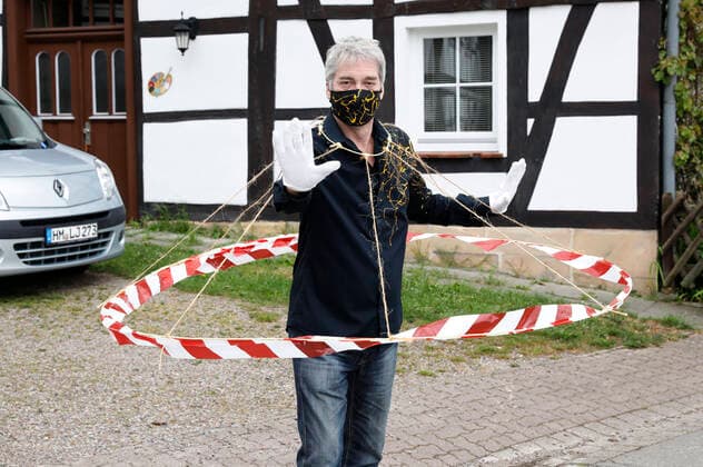 BODYART-Künstler Jörg Düsterwald in seinem Corona-Krisen-Outfit mit dem experimentellen Prototyp eines Abstandshalters. Würden alle Menschen solche Barrieren tragen, wären die notwendigen Distanzen gewahrt. Dazu trägt Düsterwald einen selbstgefertigten Mundschutz passend zum Hemd der eigenen, individuellen Mode-Kollektion aus seinem Projekt FASHION ART. Hameln, 02.05.2020